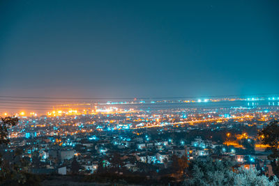 High angle view of illuminated city against clear sky at night