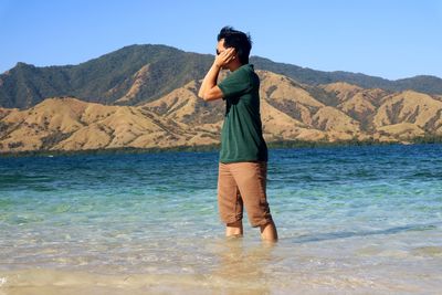 Man standing in sea against mountains