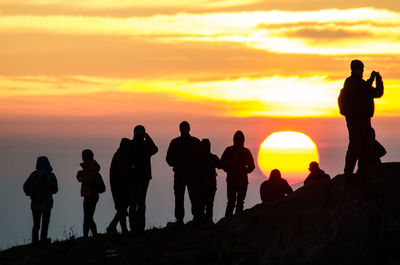 Silhouette people on mountain against sky during sunset