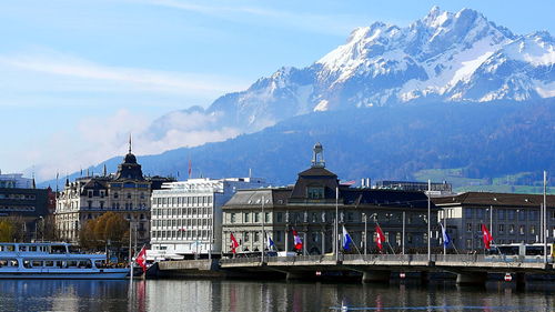 Buildings at waterfront against cloudy sky