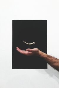 Close-up of hand holding paper over white background