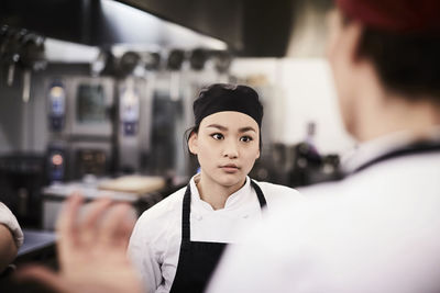 Female chef student listening to teacher in cooking school