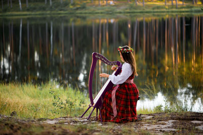 Woman playing instrument by lake