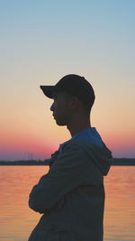 Silhouette man standing by sea against sky during sunset