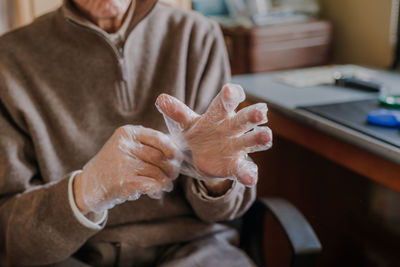 Midsection of man holding woman sitting on table at home