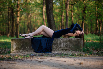 Woman lying on land in forest