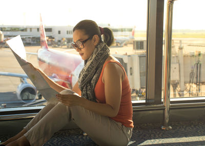 Woman reading map while sitting by window at airport