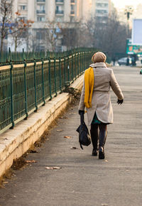 Rear view of woman walking on sidewalk in city