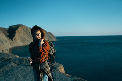 Young woman standing by sea against sky