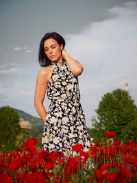 Young woman standing against sky