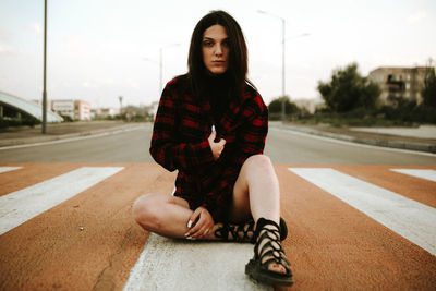 Portrait of young woman sitting on road