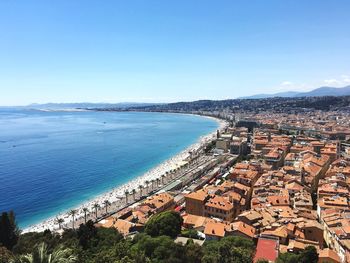 High angle view of townscape by sea against clear blue sky