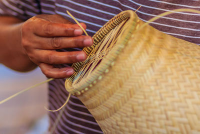 Midsection of man making wicker decoration