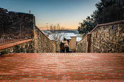 Rear view of man on wall against sky