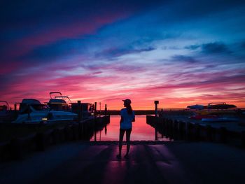 Silhouette man standing on sea against sky during sunset