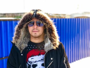 Portrait of young man wearing warm clothing against corrugated iron