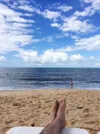 Low section of man on beach against sky