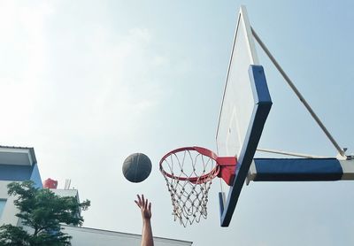 Low angle view of person playing basketball against sky