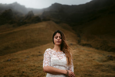 Woman standing on mountain by road against sky