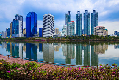 Modern buildings by river in city against sky