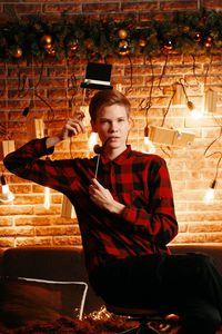 Portrait of young man sitting in illuminated building