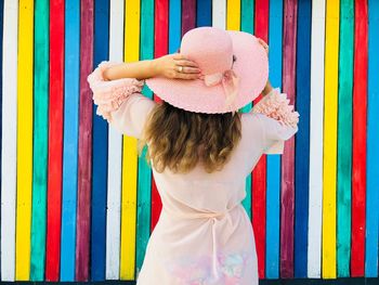 Rear view of woman wearing hat while standing by colorful wall