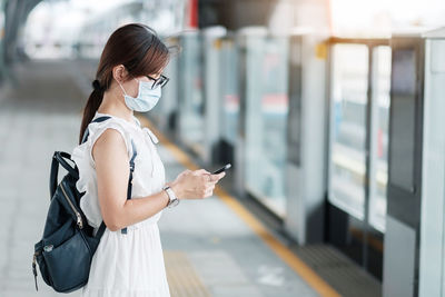 Midsection of woman holding mobile phone standing outdoors