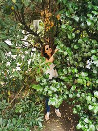 Portrait of young woman standing by leaves