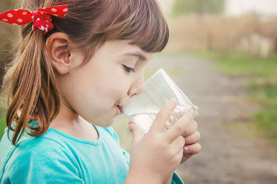 Close-up of young woman drinking milk in park