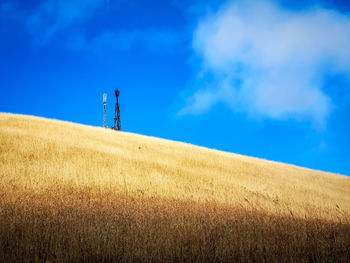 Windmill on field against blue sky