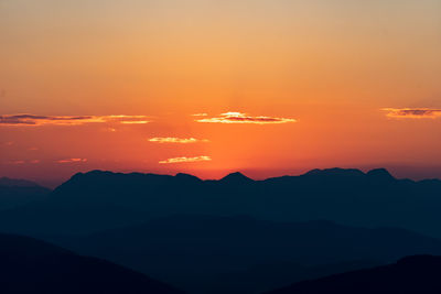 Scenic view of silhouette mountains against romantic sky at sunset