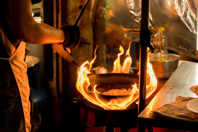 Midsection of chef preparing food in commercial kitchen