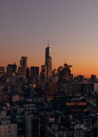 Illuminated buildings against clear sky during sunset