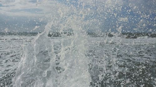 Close-up of wave splashing on sea against sky