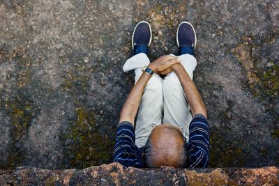 Low section of man sitting on rock