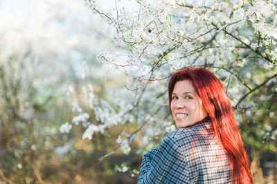 Portrait of young woman standing against trees