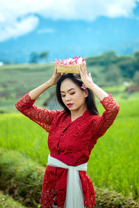 Portrait of an indonesian woman, wearing a red balinese kebaya. 