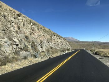 Empty road by mountain against sky