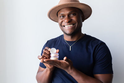 Portrait of young man holding bottle against white background