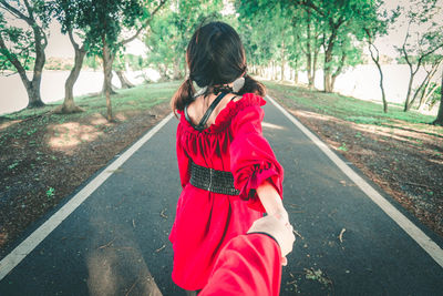 Rear view of woman standing on road against trees