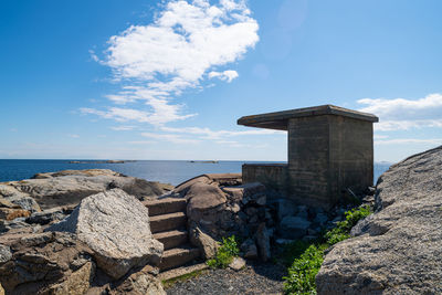Built structure on rocks by sea against sky
