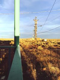 Electricity pylon on field against sky