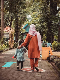 Rear view of woman walking on footpath