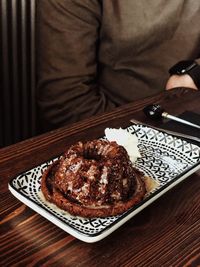 Midsection of person with chocolate cake on table