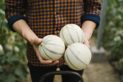 Close-up of person holding pumpkin on field