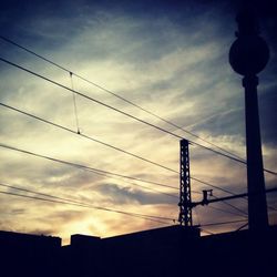 Low angle view of electricity pylon against cloudy sky