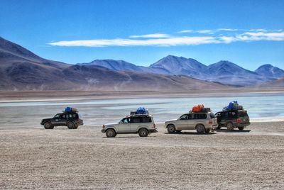 Scenic view of 4-wheel cars parked in the desert against sky