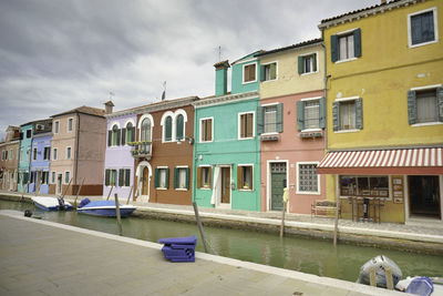 Buildings by canal against sky in city