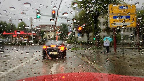 Cars on road seen through wet window in rainy season