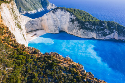 Aerial view of navagio beach - shipwreck beach - on zakynthos island, greece. tourists on cliff edge